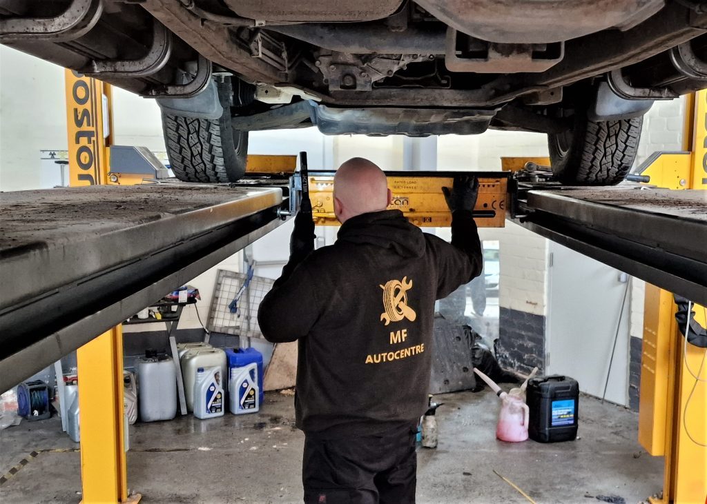 Checking the underside of a car up on the ramp