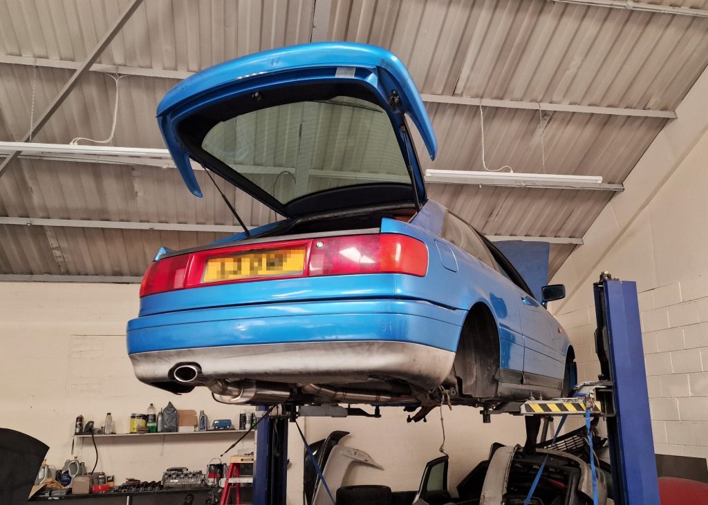 A blue coupe up on the lift